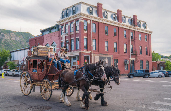 A man and woman drive a historic horse-drawn carriage through downtown Durango, Colorado, on an overcast day. 