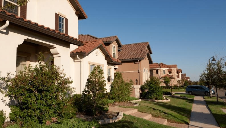 A row of residential homes in Las Colinas, Irving, Texas. They’re all a similar style with tiled roofs, stucco exterior, and a two-story design.