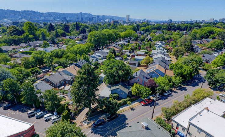 Aerial view of the popular Ladd’s Addition neighborhood in Portland, Oregon. It’s springtime and mature trees throughout the neighborhood are full of vibrant, green leaves. The streets of the neighborhood are set at an angle, unique to Ladd’s Addition.