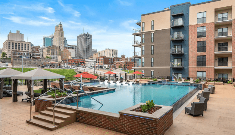 View of the community pool and surrounding apartments at 531Grand, an apartment and condo building in Kansas City’s River Market District. Tall downtown buildings can be seen from the deck of the building’s pool. 