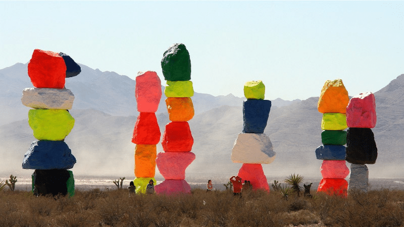 Tourists are taking pictures at the Seven Magic Mountains attraction outside of Las Vegas, Nevada. The large boulder stacks reach several stories high and each is painted in a unique series of vibrant colors. 