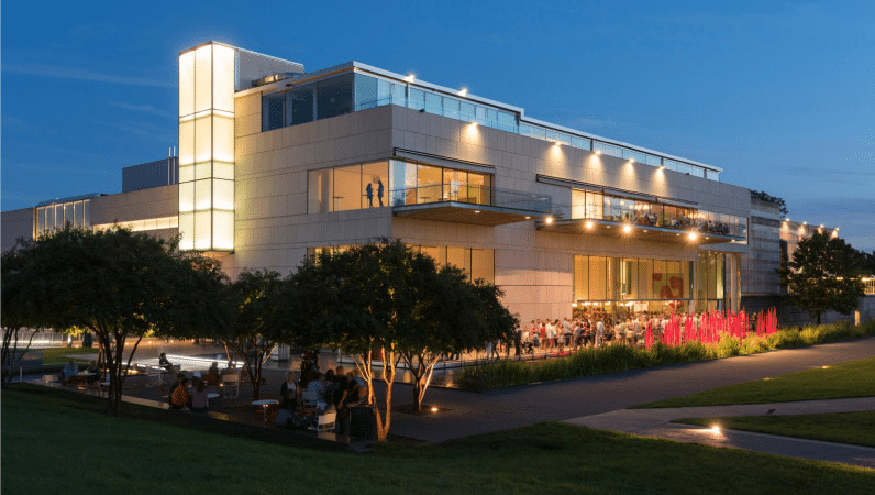 The beautiful Virginia Museum of Fine Arts after sunset. Interior and exterior lights illuminate the modern design of the building as patrons are gathering in the courtyard.