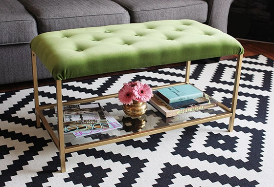 A green and gold DIY ottoman made from an IKEA coffee table, foam, and fabric.