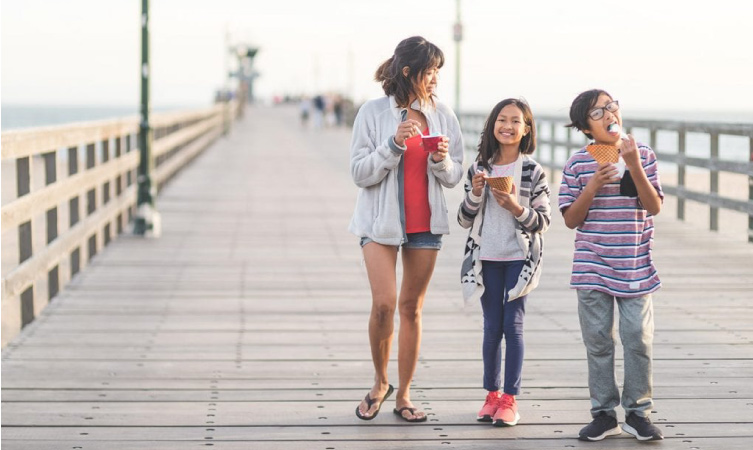 A mother and her two children are enjoying ice cream treats on the Santa Monica Pier in Santa Monica, CA.