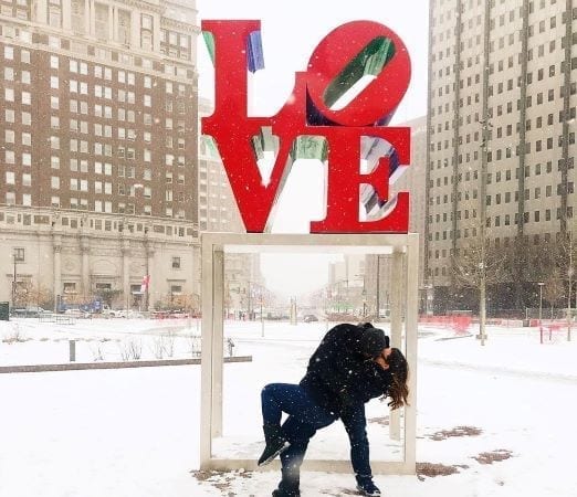 A couple kisses under the LOVE sculpture in Philadelphia's JFK Plaza.