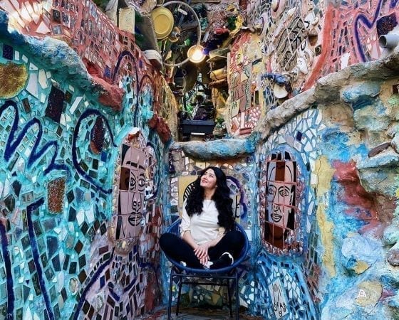 A woman is sitting in a chair, admiring the mosaic walls at Magic Gardens in Philadelphia.