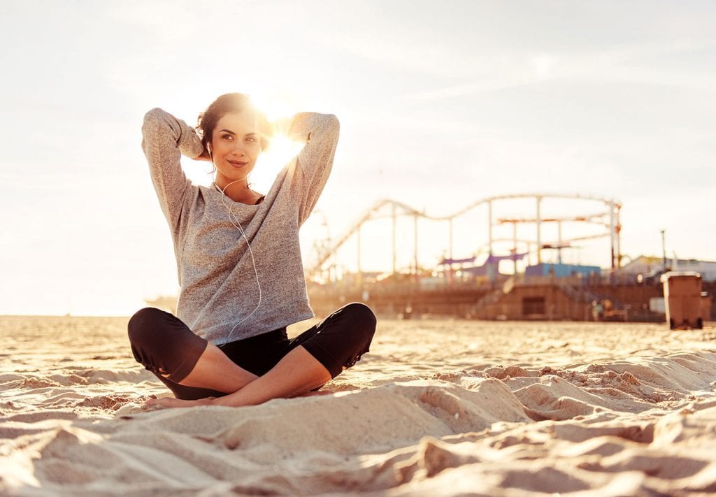 A woman relaxing on a beach in L.A. with the Santa Monica Pier behind her