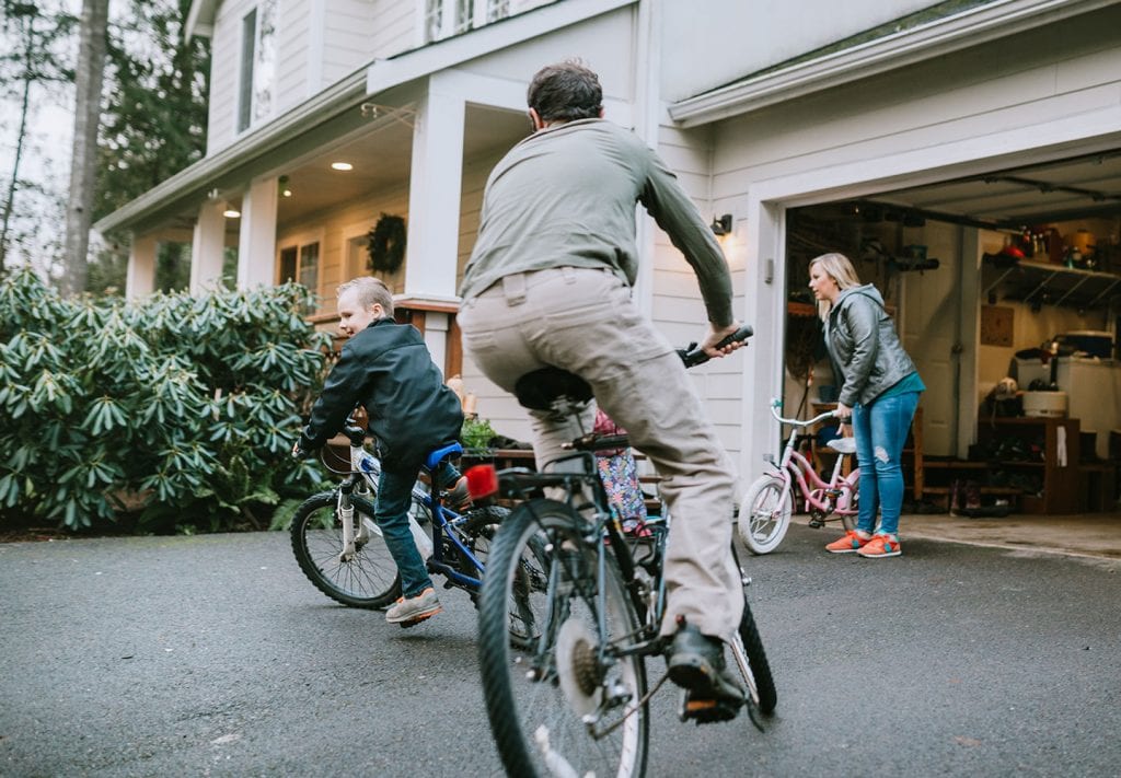 A young family ride bikes in their driveway. 