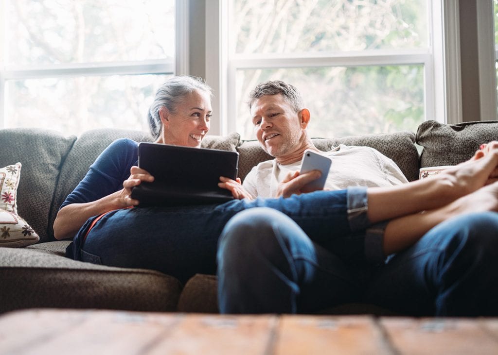 couple sitting on couch with tablet and iphone