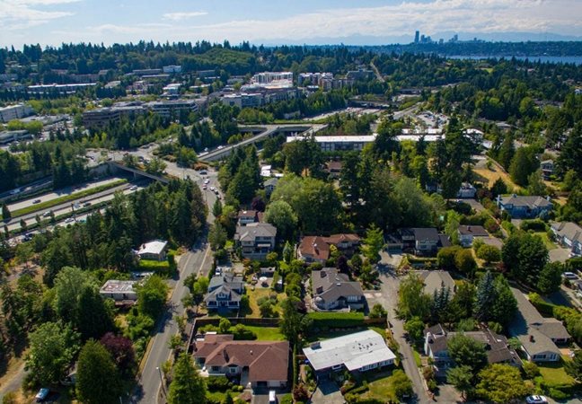 Aerial view of a Seattle suburb with houses in the foreground and Downtown Seattle’s skyline across in the background.