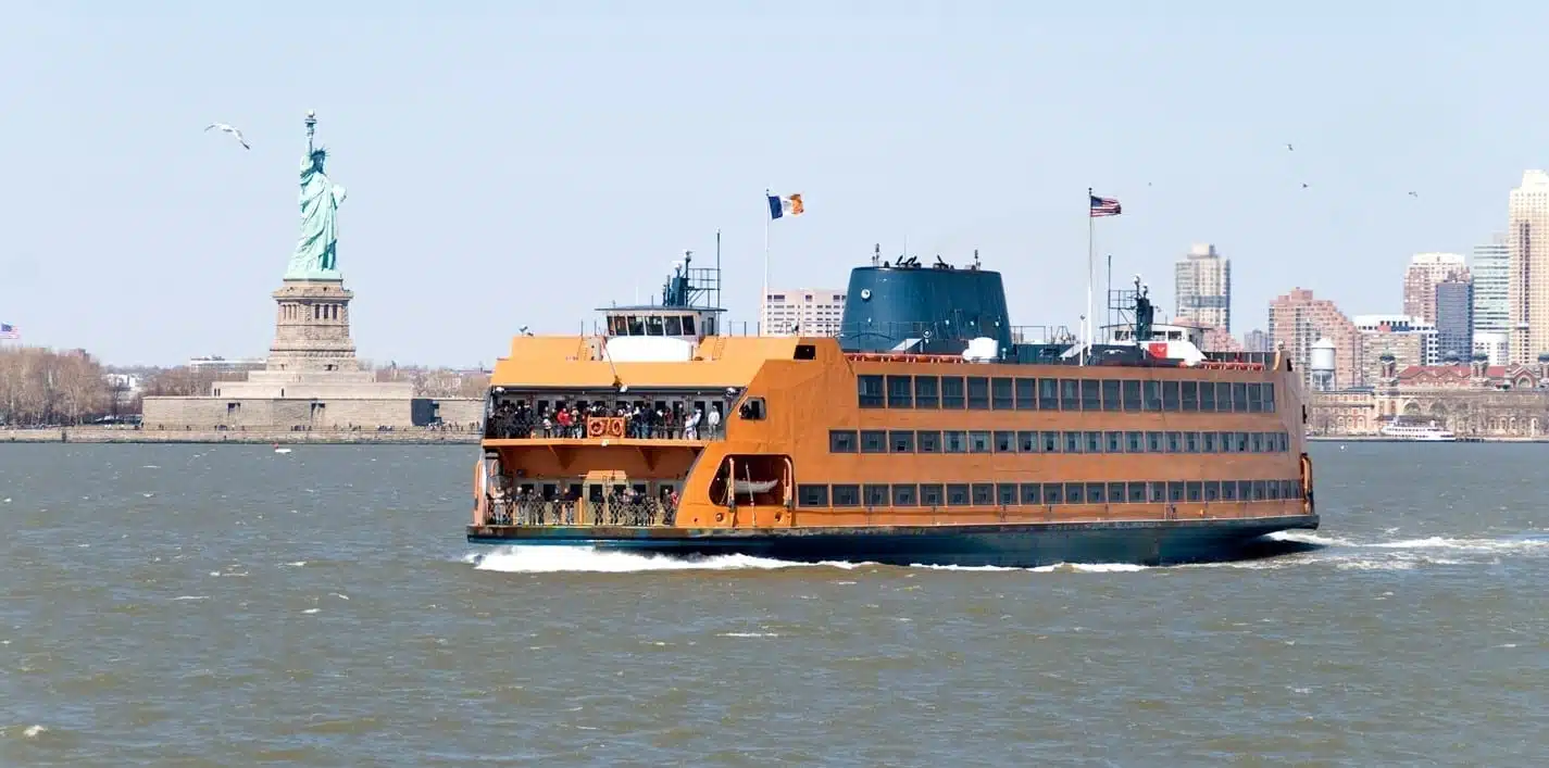 ferry on the water in front of the Statue of Liberty