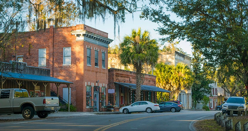Downtown Micanopy in the late afternoon. A two-story red brick building stands over the road, welcoming potential antique hunters.