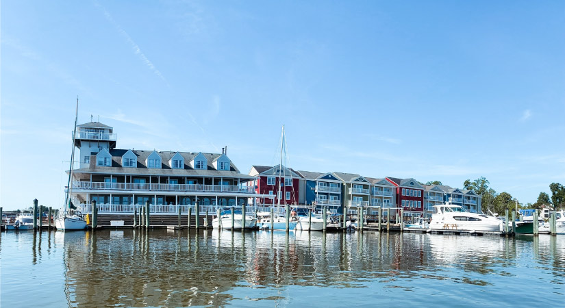 View from the water of docks and the Smithfield Station Hotel in Smithfield, Virginia. There are power boats and sail boats docked in the marina.
