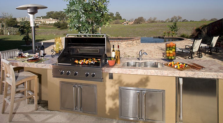 A deck remodeled to have an outdoor ktichen, complete with grill, sink, and counter space