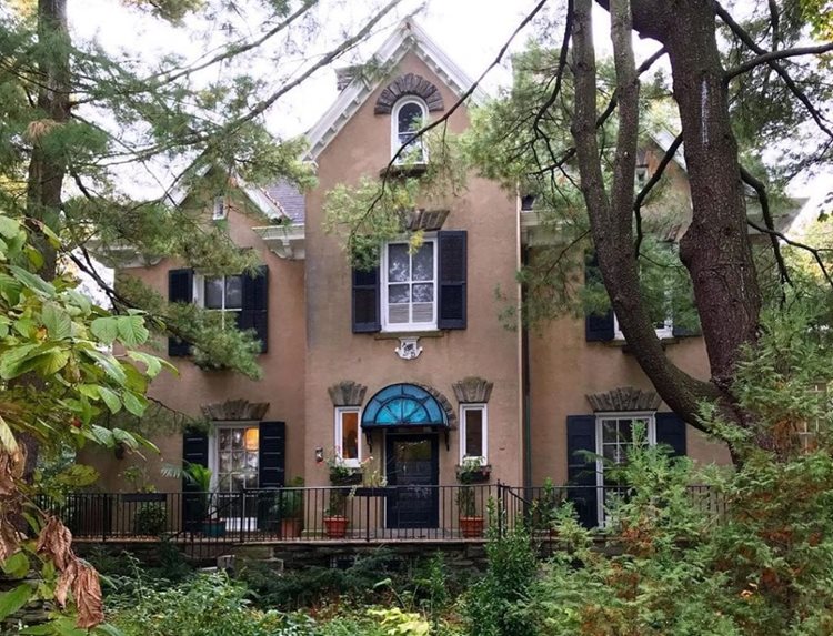 A large, upscale home in the Chestnut Hill neighborhood of Philadelphia. The home features a stucco exterior and decorative elements above the door and windows.