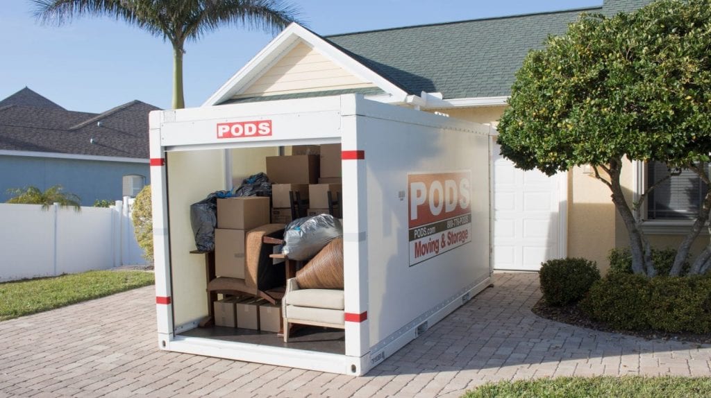 A full PODS moving and storage container sits in a driveway.