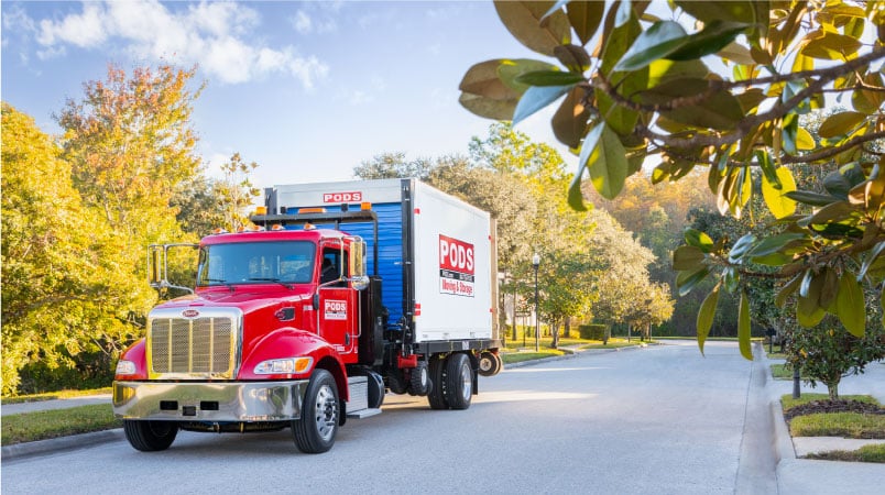 A truck carrying a PODS container drives down a Florida road, welcoming in the next small-town Florida resident.