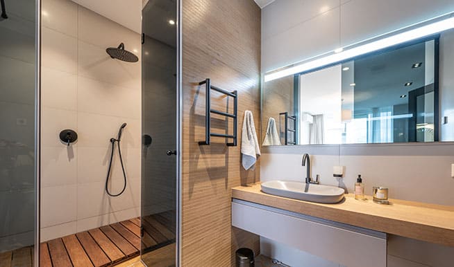 Wooden accents throughout this bathroom, especially a wooden-plank floor in the shower, give the space a warm, relaxing feel.