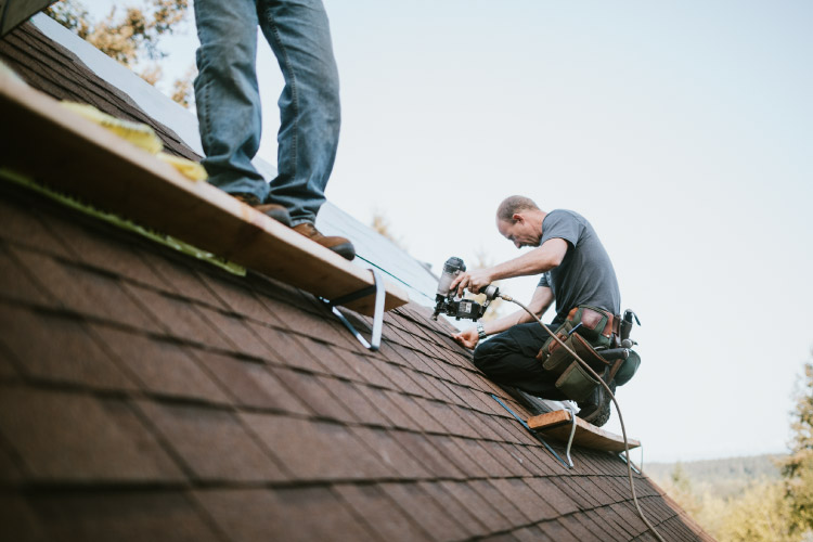 A home remodeling contractor and one of his team members are in the process of installing a new roof on a residential home