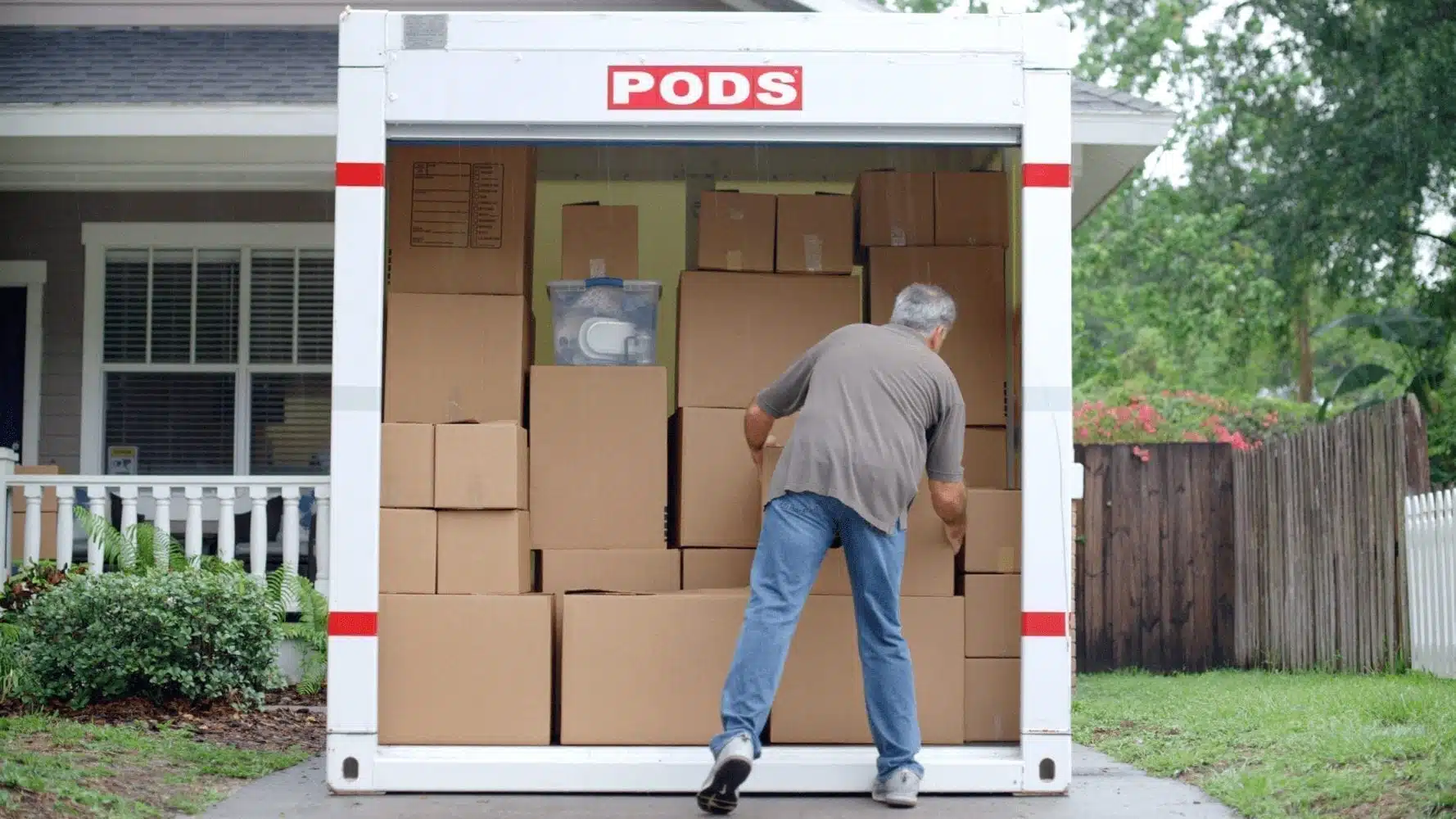 A man loading boxes into his PODS portable storage container, which is conveniently located in his driveway.