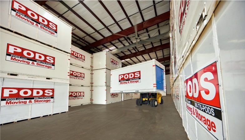 A PODS portable moving and storage container is being positioned by forklift in a PODS Storage Center.