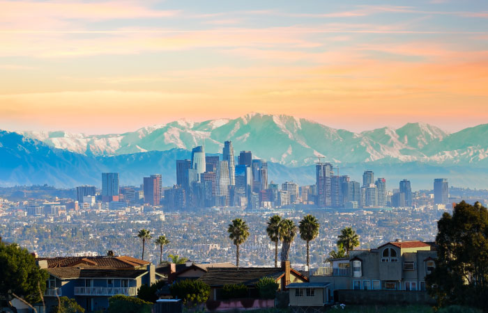 The Los Angeles skyline and distant mountains seen from across the rooftops of residential homes. 