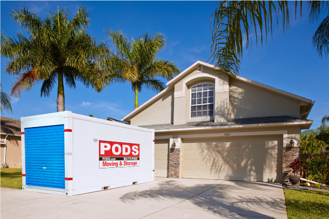 A PODS portable moving container is positioned in the driveway of a two-story Florida home that the occupants are moving out of.