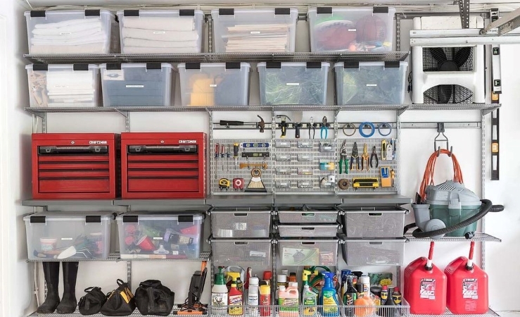 An entire garage wall, filled top-to-bottom with shelving. Many of the shelves hold clear plastic bins, filled with like items. Other shelves host tool boxes, cleaning supplies, hanging tools, and other items. Everything is well organized and easy to find. 