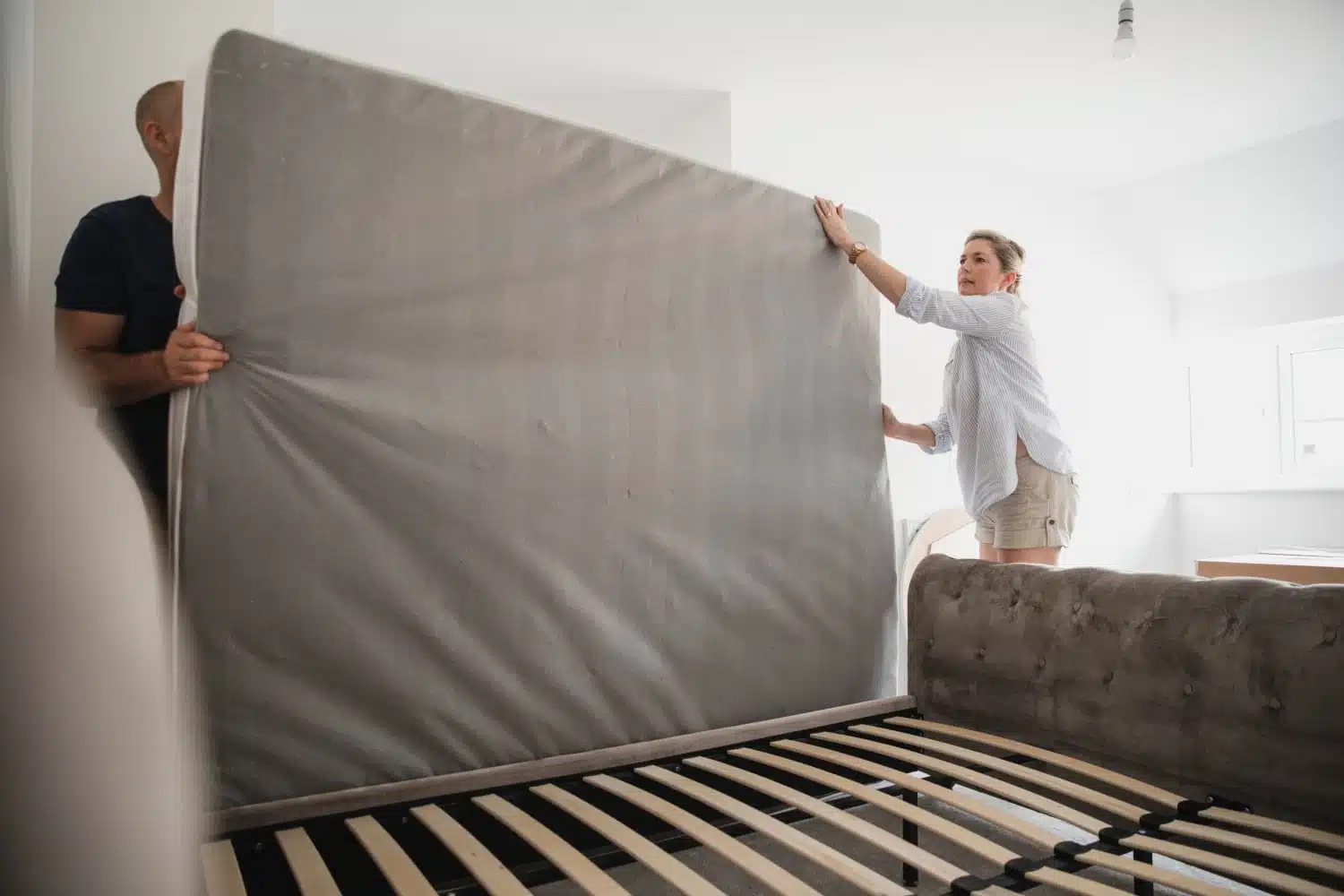 A couple moving a mattress and determining how to pack a mattress for moving