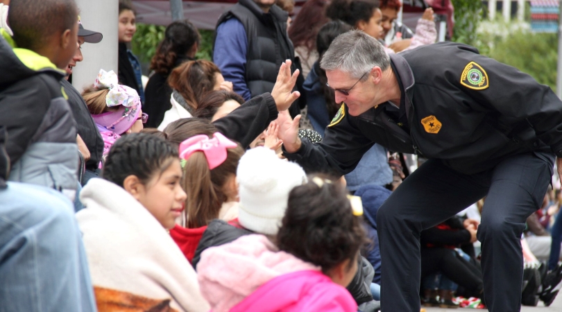 A police officer is interacting with a group of local kids, high-fiving their hands, during a presentation in Houston, Texas. 
