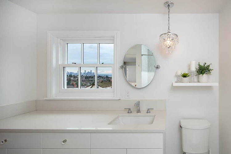 all-white bathroom with sink, vanity, mirror, and window view of city skyline