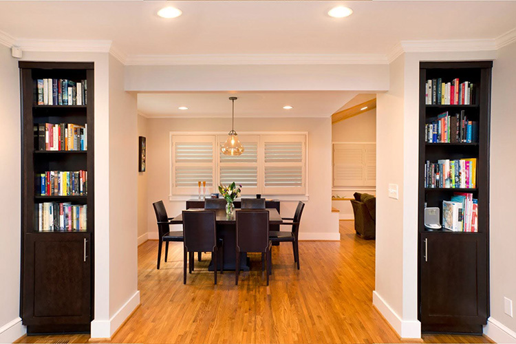Built-in bookcases lead to a dining area with hardwood floors and a family dining table