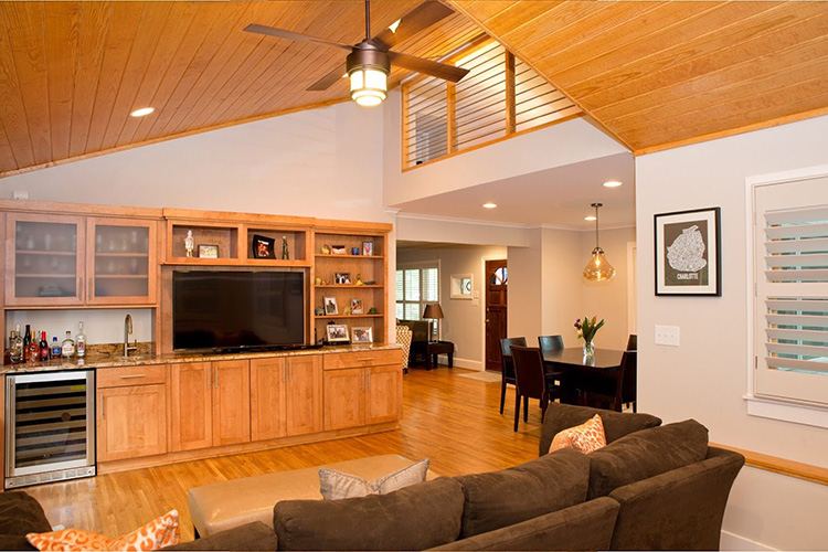 A wall-unit entertainment center, built-in wet bar, and wine refrigerator in a family room with large couch 