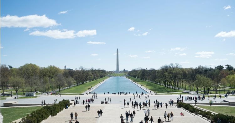Visitors gather around The Lincoln Memorial Reflecting Pool in front of The Washington Monument, an iconic aspect of life in Washington, D.C.