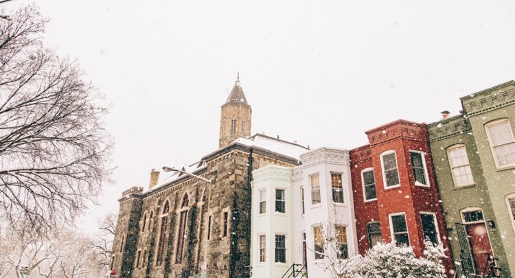 A corner church and three connected row houses look tranquil during a spring snowfall in the Capitol Hill neighborhood of Washington, D.C.