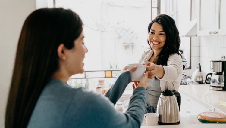 An Airbnb host is offering her guest a cup of coffee in the morning.