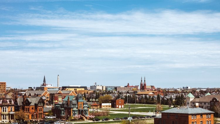 Distant view of the Brush Park neighborhood in Midtown Detroit. Many of the homes are old, three-story brick homes, and there are a few steeples in the distance. 