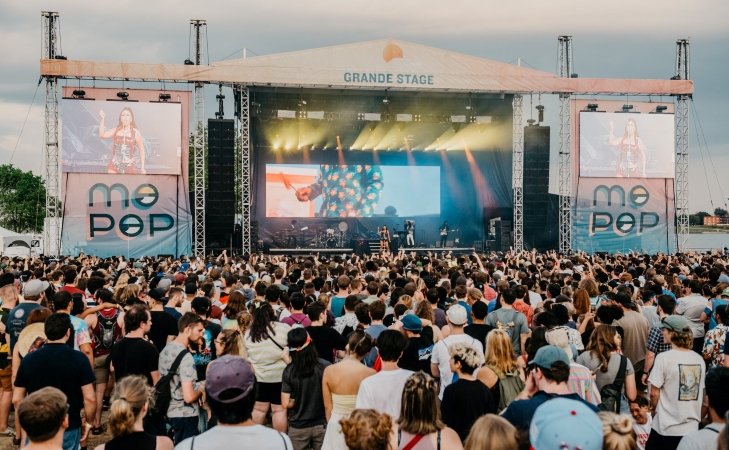 A musical artist is performing in front of a packed audience at Mo Pop Festival in Detroit.