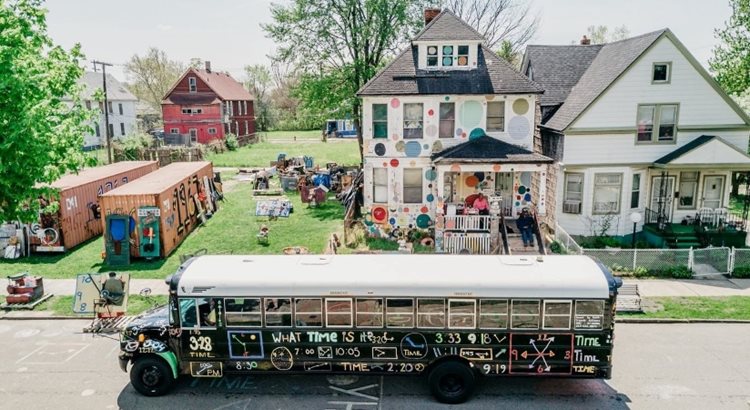 An elevated view of the Heidelberg Project in Detroit, featuring a colorfully decorated bus, house, and many, many pieces of art on display.