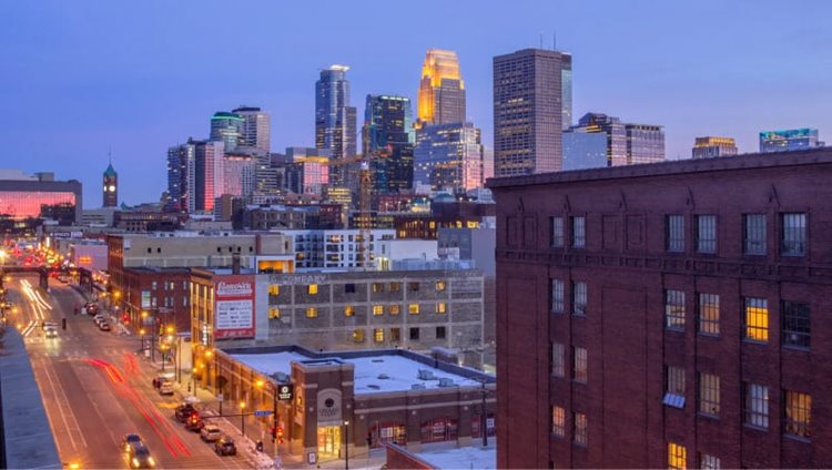 The North Loop neighborhood of Minneapolis. The buildings are older, made of brick, and the downtown skyscrapers loom in the distance