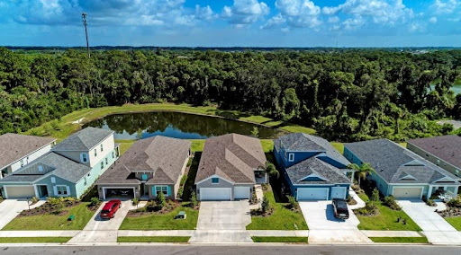 A row of large, two-story homes in Bradenton, Florida, back up to a small pond and a wooded greenspace.