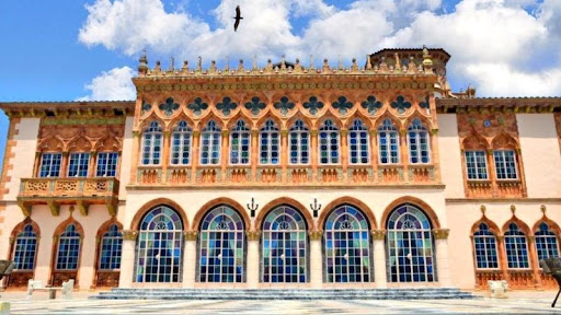 A large bird is soaring over the majestic Ringling Museum of Art on a sunny day in Sarasota, Florida.