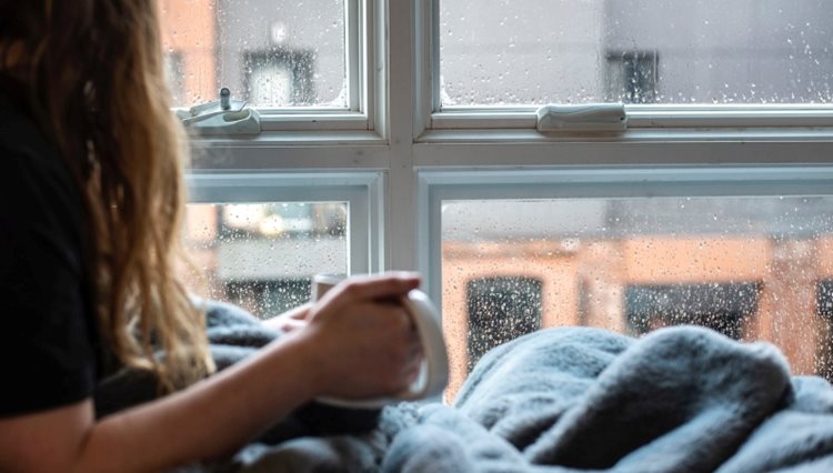 Close-up of a woman staying warm and cozy in her home on a rainy day. 