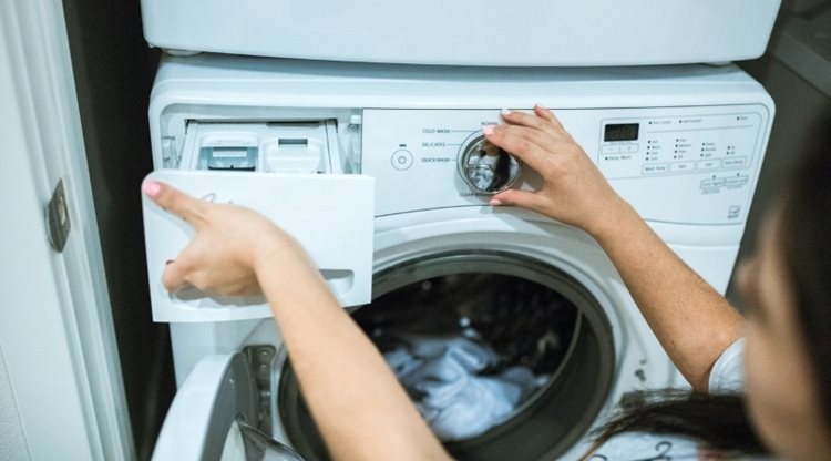 Close-up of a woman using a front-loading washing machine to clean a load of laundry.