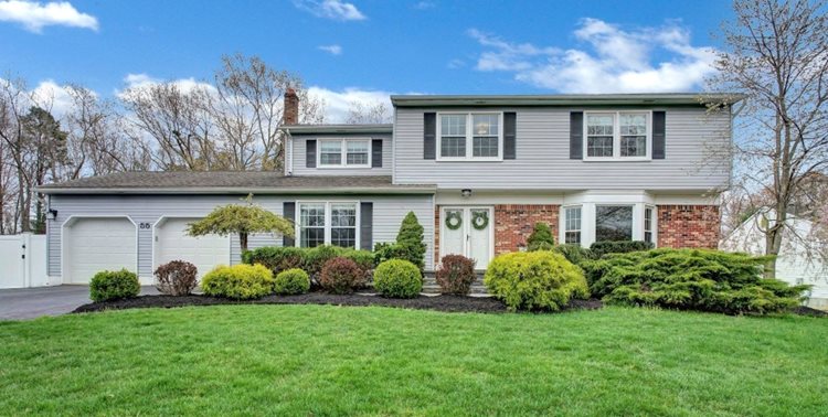 A two-story home in Manalapan, New Jersey, features a brick and siding exterior, a two-car garage, and professional landscaping.