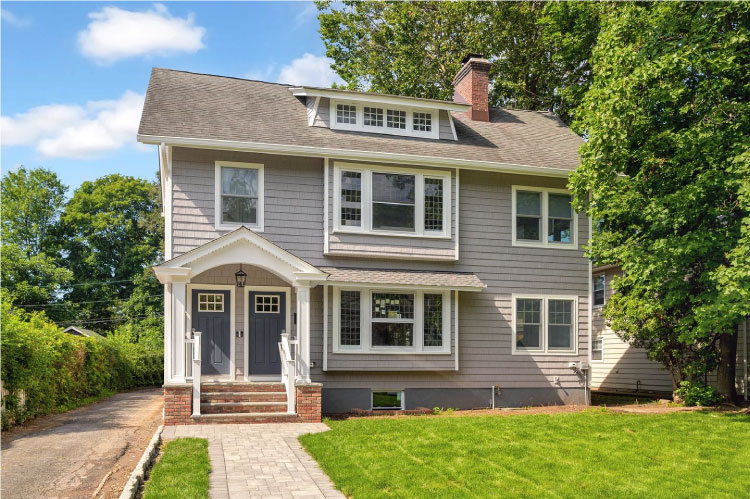 A Colonial-style duplex in Montclair — one of the best places to live in New Jersey — featuring a covered entryway, windowed attic, and a chimney.