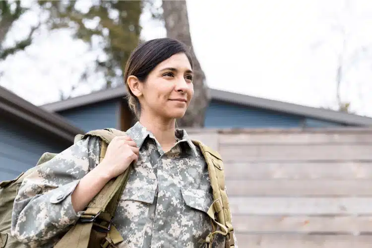 A servicewoman is in uniform with a pack over her shoulder, smiling as she thinks about her upcoming PPM.