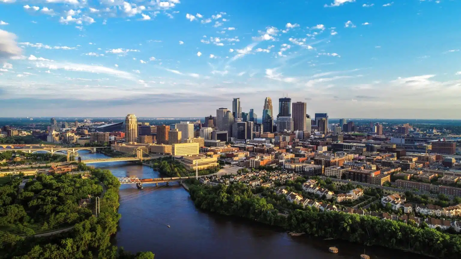 Aerial view of the Minneapolis skyline, featuring several city bridges stretching across the Mississippi River.