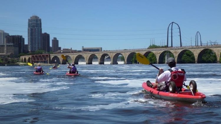 Four locals enjoy an afternoon kayaking on the Mississippi River in Minneapolis, Minnesota.