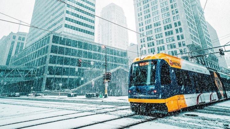 A METRO light rail train in Minneapolis travels along snow-covered city streets as a winter storm blows through the city. 